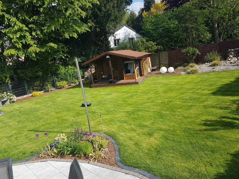 Gepflegte Rasenfläche mit Beeten und Gartenhaus in Essen